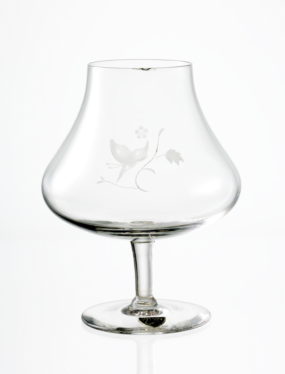 Design: Nils Landberg.
Aromglas. Klockformad kupa med graverat motiv: fjäril och blomma. Lågt ben. 
Fabriksmärke: blå botten med guldtext.