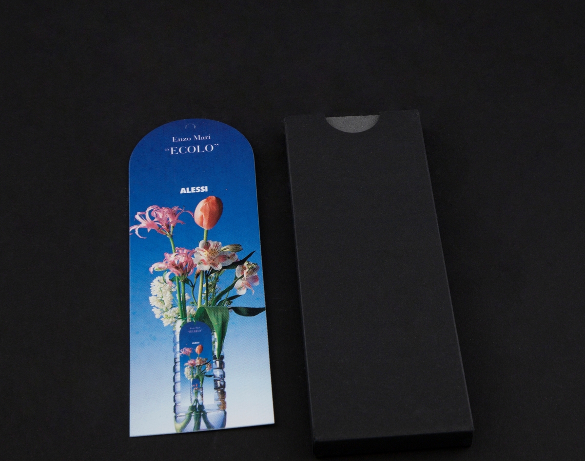 Liten, svart og rektangulær instruksjonsbok med tittelen: "ECOLO". Inkludert er et kort med bilde av blomster i vase.