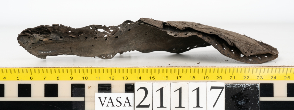 Delar och fragment av stövel.
Ett fragmentariskt ovanläder. En botten bestående av tre löst liggande sulor. Ett fragmentariskt framstycke till stövelskaft. Ett 30-tal fragment och delar från klack, sulor, inlägg mm.