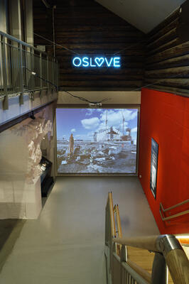 Foto av utstilling på Bymuseet i Oslo. Neonskilt hvor det står OSLOVE.