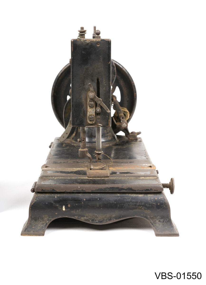 Symaskin med sveiv i svart jern. Den er festet med to hensgler på en solid sokkel av 6 cm i støpejern.   
Muligens produsert av GROVEN & BAKER (Boston, USA), produsenter siden 1851.