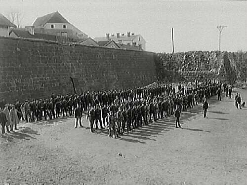 Uppställning av militärer nedanför fästningsmuren åt norr.