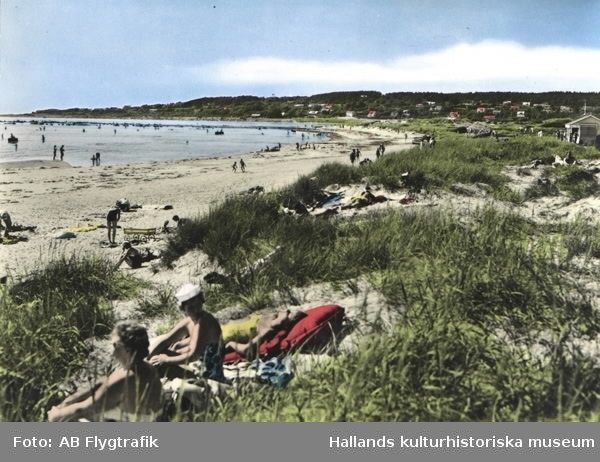 Vykort, "Haverdals strand". Bild 1: Kolorerat. Bild 2: Sv/v. Strandvy med badande människor. Sanddynor. Bebyggelse i bakgrunden.