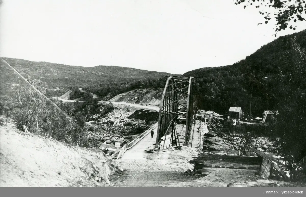 Her ser vi Neiden bru i 1938. Trebrua ble brukt som monteringsbru. Her er fagverket ferdig montert. Anlegg: Hesseng-Neiden.