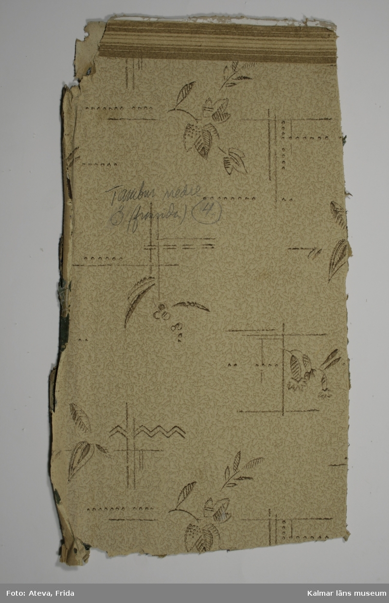 KLM 43762:2. Tapet av papper.Tryckt tapet med melerad botten i bruna färger. Mönster med stiliserade blommor och blad i brunt samt streck, prickar och zickzack-linjer, även de i brunt. Överst smal bård, B 3,5 cm, med vågräta bruna och beige streck. På framsidan står skrivet med blyerts: Tambur nedre Ö (framsida) 4. Närmast synliga underliggande lager har tryck i svart och gult på ofärgad botten. Närmast underliggande lager har tryck i ultramarinblått på ofärgad botten. Under detta ljusblått tryck på genomfärgat grönt papper. I princip likadan lagerföljd som KLM 43762:1.