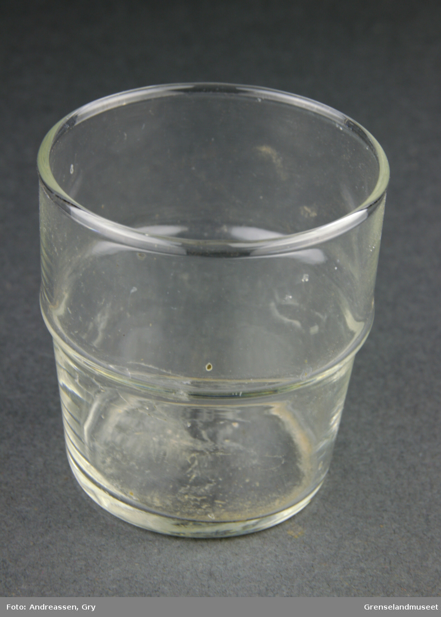 Blankt glass som smalner mot bunnen. Utvider seg med en markert kant ca midt på. 