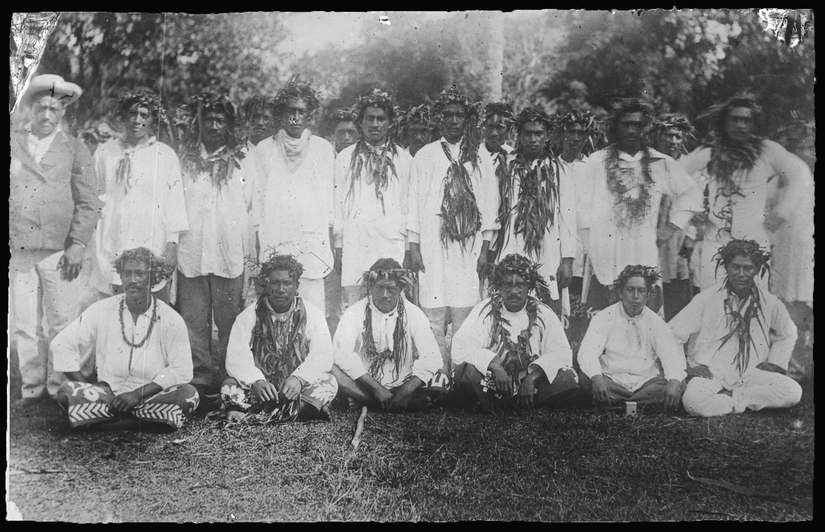 Bilden förställer ett grupporträtt med män från Tahiti som är smyckade med blomkransar.