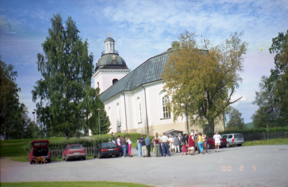 En grupp människor står på parkeringen vid Färila kyrka,  5 augusti 2000.