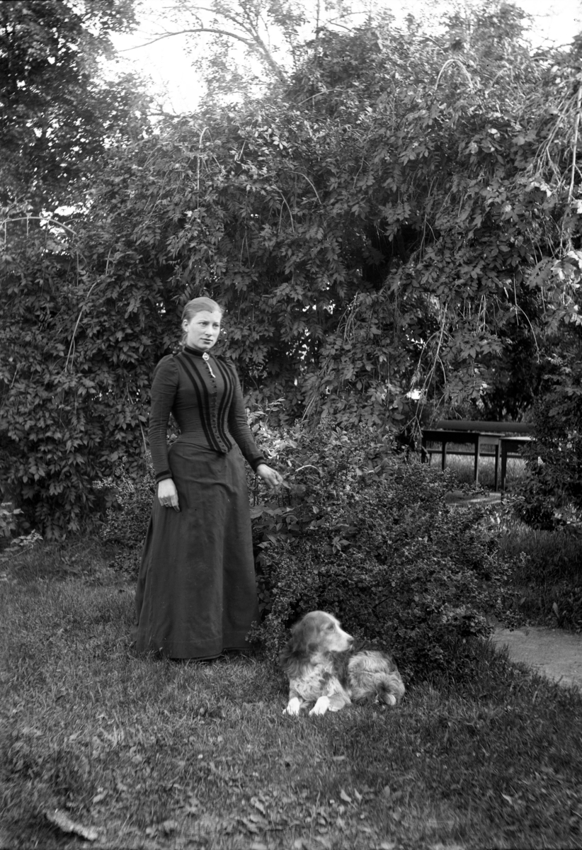 Ung kvinne og Jeia Homanns hund ved hengeasken i plenen på Berg gård, Kragerø.