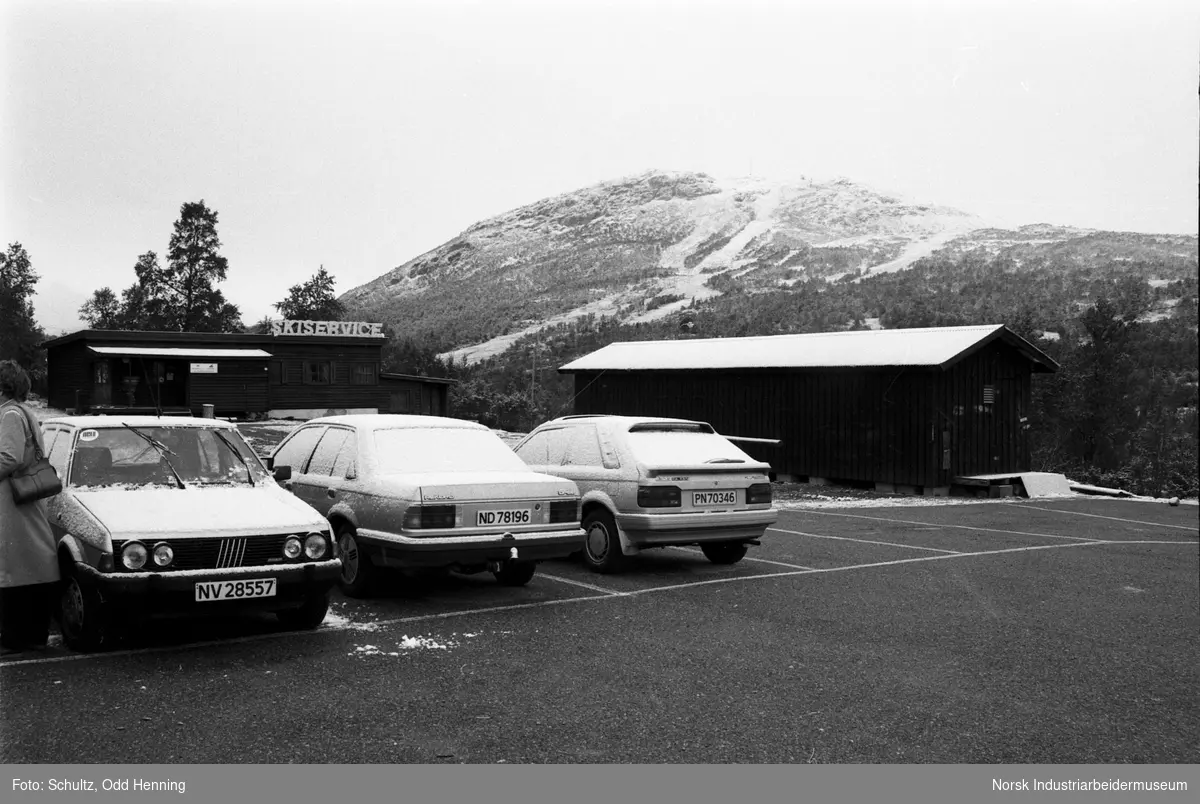 Bilen parkert en parkeringsplass, antatt under tur for pensjonister. I bakgrunnen ser en et anlegg for alpint skisport.