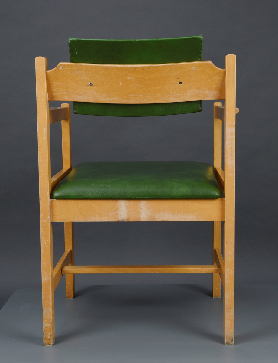 To identiske lenestoler med armlener. De er firkantet på form. Stolene har delvis åpen rygg, men øverst er det montert på en svakt buet ryggplate med enkel utskjæring. På ryggplaten er det en pute av grønn skai fylt med skumgummi. Ryggputen måler 33,5x21cm. Setet har også fyll av skumgummi og trukket med grønn skai. Bunnplaten i setet er av kryssfiner. Setet er firkantet med avrundede hjørner og det stikker noe utenfor stolens ramme. Stolene har firkantede armlener med enkel utskjæring og de er åpne i sidene. Ryggstøet går ned i to firkantede bein bak. Også i front er det to firkantede bein. Nede på stolene er det en sprosse i hver side og en på midten slik at de danner en H-form.