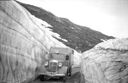 1937-modell Reo lastebil m/hus køyrer gjennom ei snøskjering