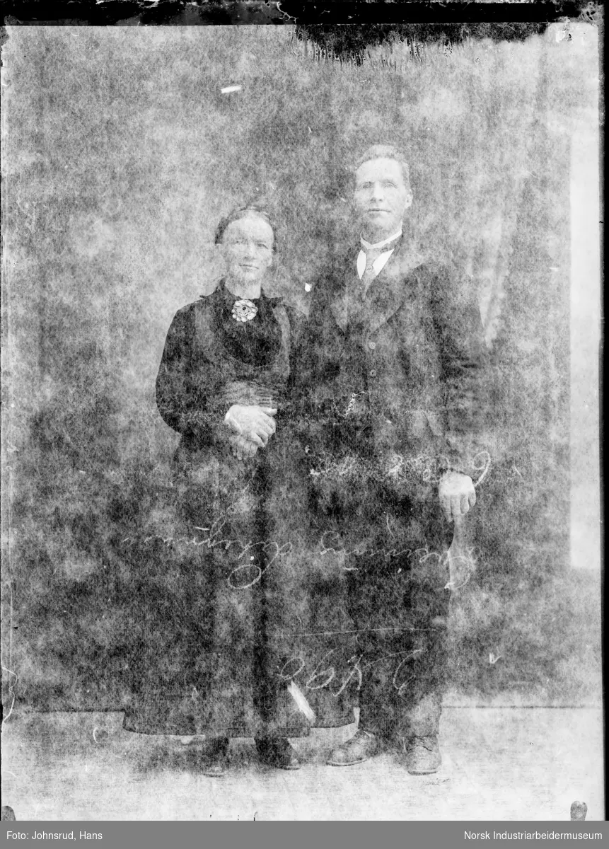 Portrett av stående mann i dress og kvinne i bunad.