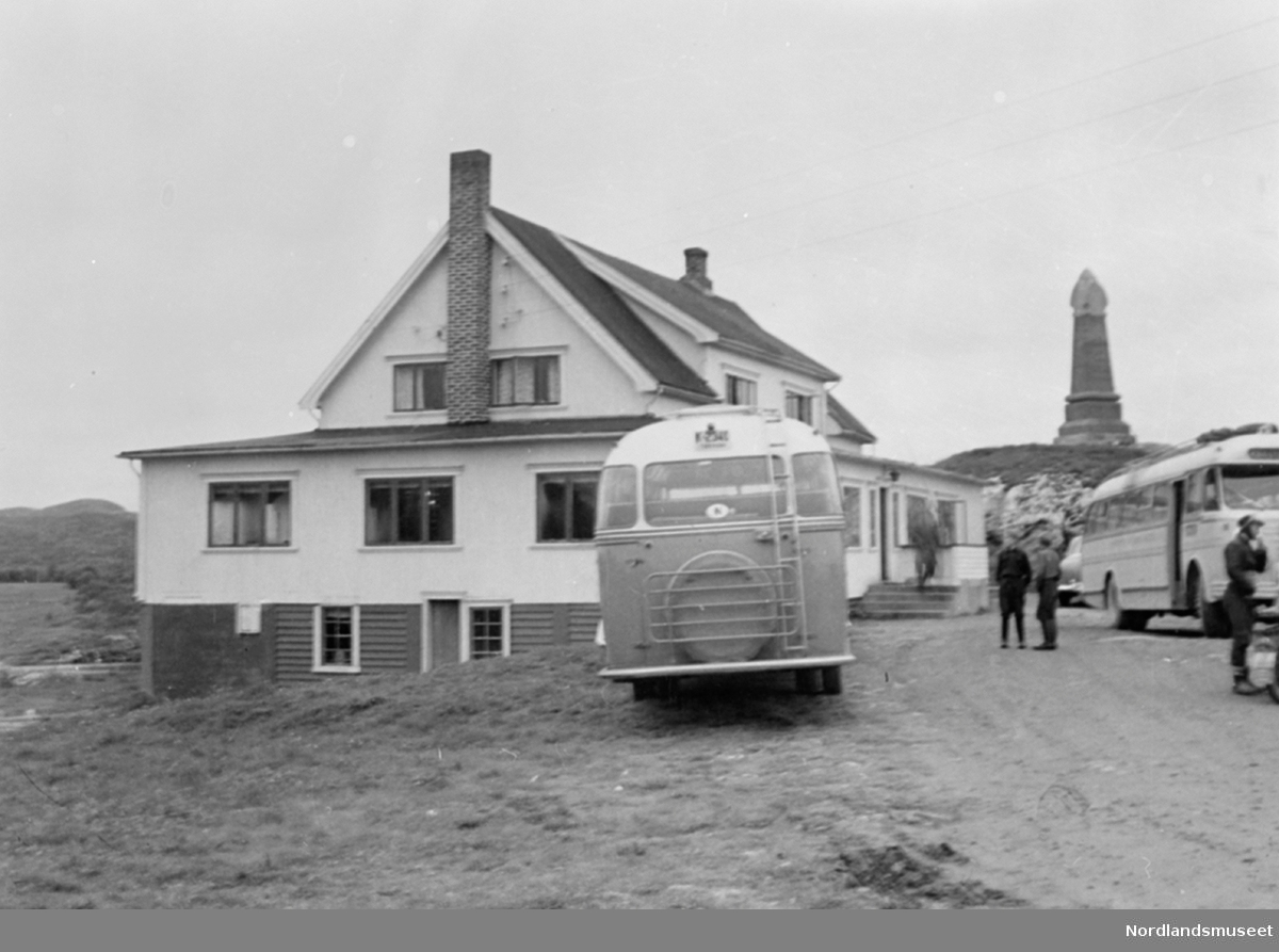 Saltstraumen turisthotell. 2 busser og 3 personer foran hotellet. Ellers minnestøtta til Kong Oscar II's besøk på høyden til høyre.