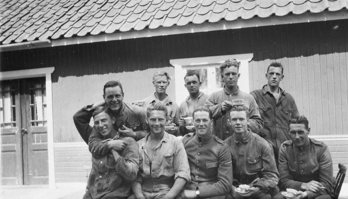 Porträttfoto av tio militärer under kafferast, utomhus, 1910-1920-tal.