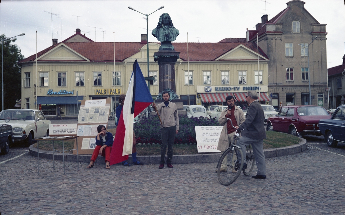 Protest mot Sovjets ockupation av Tjeckoslovakien, ettårsdagen troligtvis. Liten fotoutställning, protestlista att skriva på och slagord.

I kv Gustaf ligger Gustavs konditori, BW Radio - TV och Alingsås konsthall.