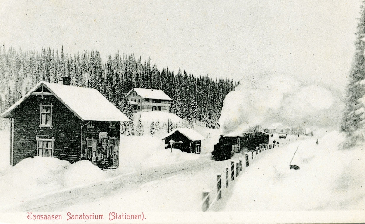 Persontog trukket av et av Valdresbanens damplokomotiver på Tonsåsen stasjon. Tonsåsen sanatorium i bakgrunnen