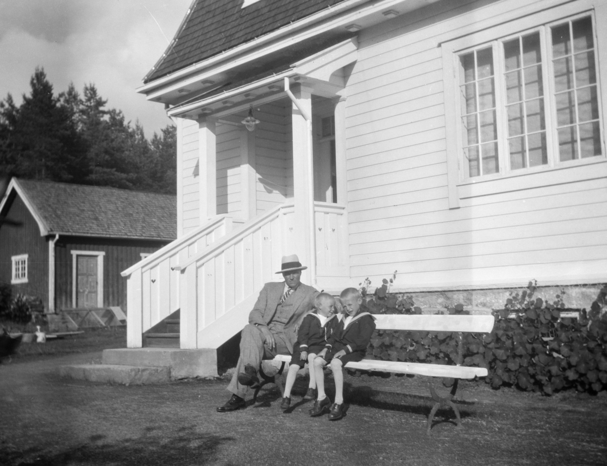 "Edvard M. H. Skotte" med to smågutter utenfor et hus