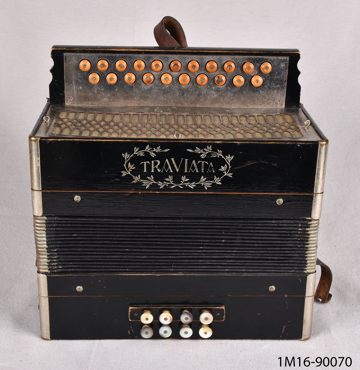 Dragspel, litet två radigt knappdragspel, durspel med endast åtta basknappar, fyra i varje rad. Spelet som är märkt "Traviata" är enligt uppgift från tiden mellan 1905 och 1910, materialet är huvudsakligen trä med metallbeslag och bygel av läder.