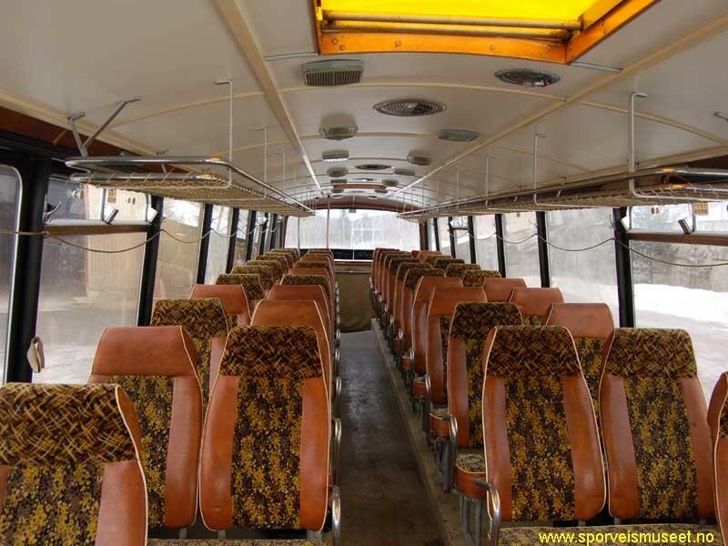 Buss i ulike grønnfarger med enkeltdører i front ved sjåfør og en bakerst i bussen. Interiøret består av rader med to seter på hver side av midtgangen i brun farge og mønstret stoff, i tillegg til lyst tak og hyller til hatter og bagasje. 