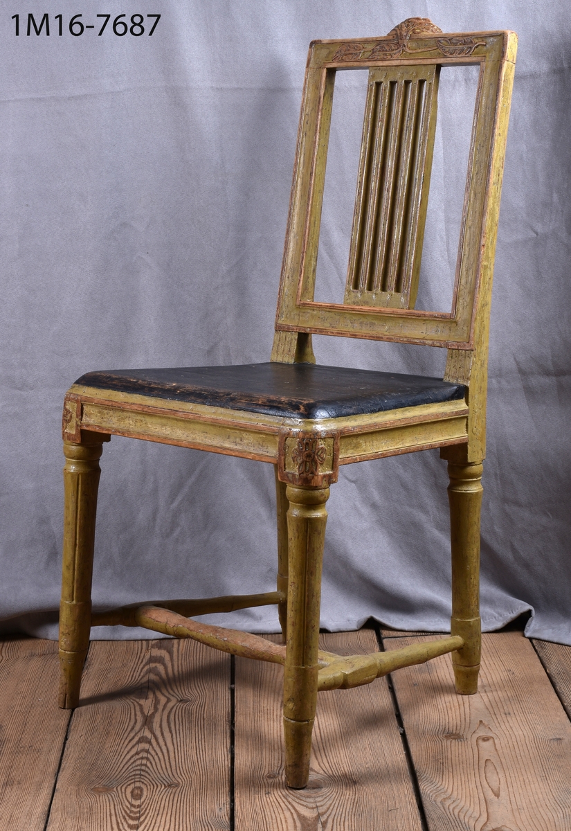 Gråmålad gustaviansk stol med svart sits, svarvade ben med kannelyrer, svarvat benkryss.Genombruten rygg med 4 st spjälor, skuret krön med blomm och bladmönster.