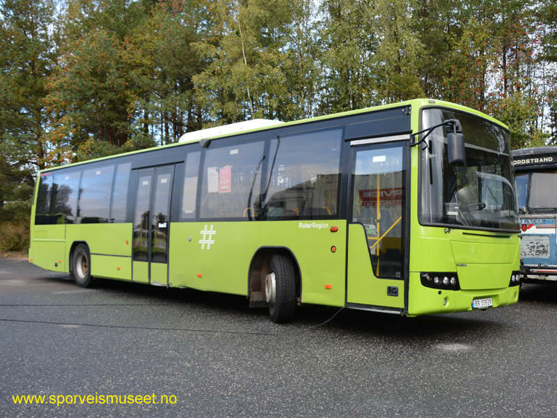 Grønn og svart buss med enkeltdør i fremme og dobbeltdør i midten. Interiøret består av grå overflater og blå seter. 

