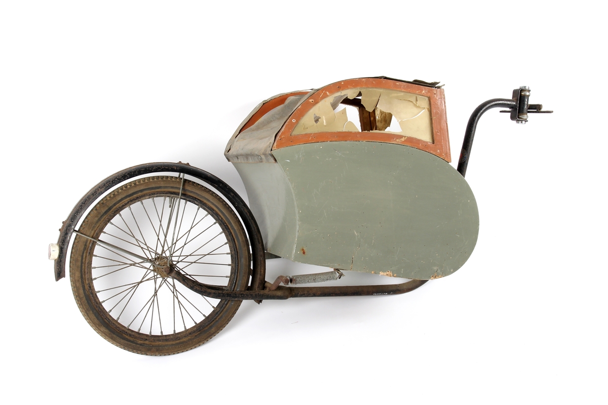 Sykkelvogn på ett hjul og med fjæring. Vognen har vinduer og plass til ett barn.