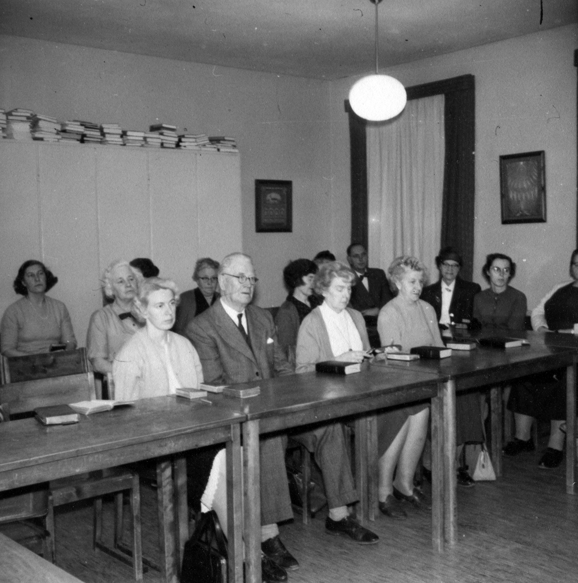 Bild på flera män och kvinnor som sitter på rad och lyssnar prosten Otto Hermansson under en bibelstudiekväll hösten 1961.