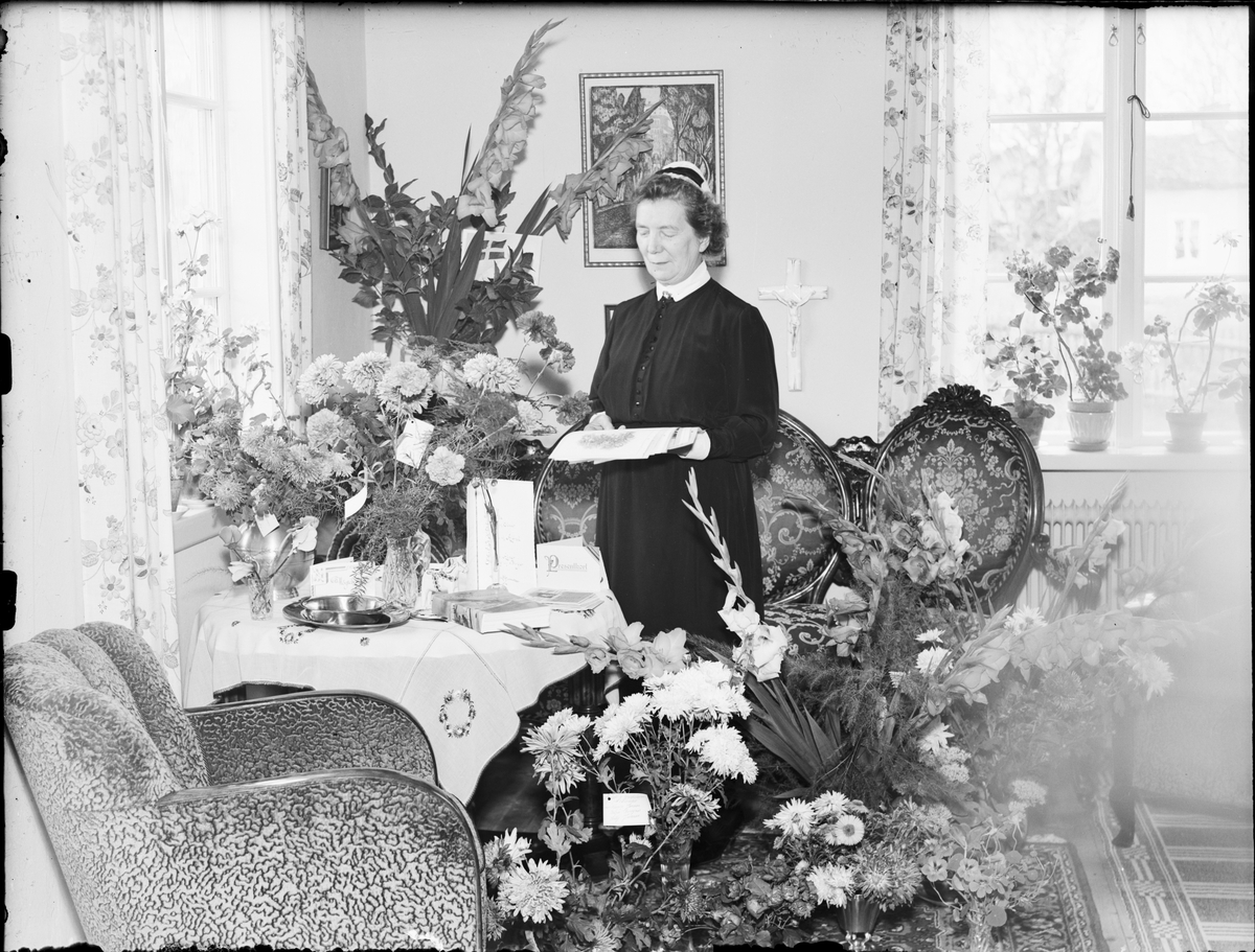 Evy Andersson omgiven av blommor, Östhammar, Uppland 1935