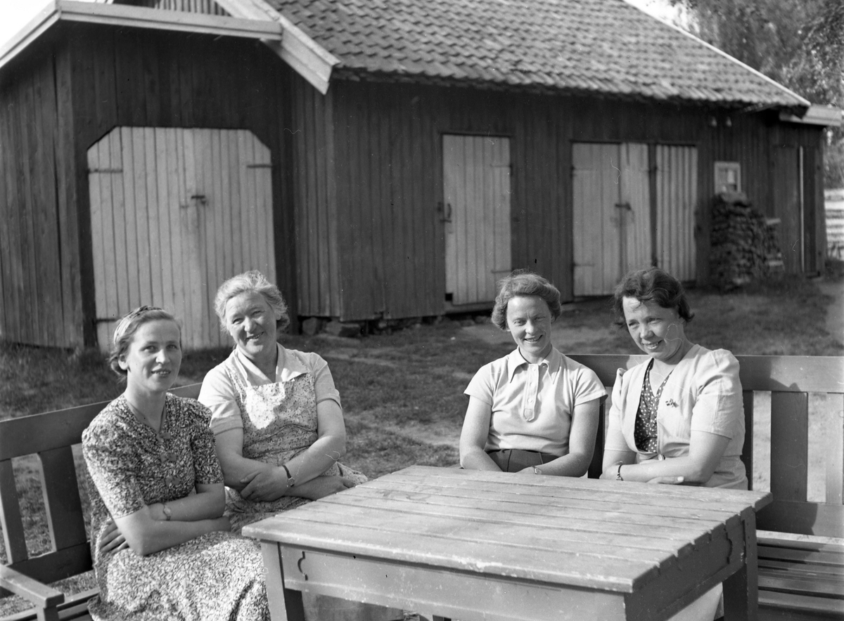 En gruppe kvinner sitter rundt et bord utendørs.