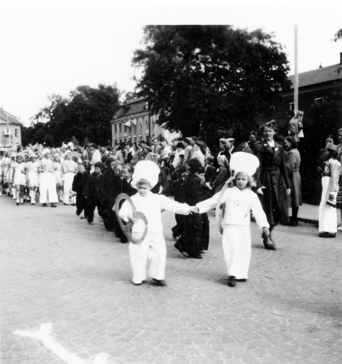 Barnens dag firande i Alingsås 1938. Flickor och pojkar utklädda till bland annat sotare och bagare i parad förbi folksamlingen.