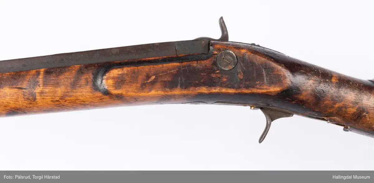 Gevær med perkusjonslås og kassepipe. Kan ha vært ombygd fra flintlås. 
Fra låsen til siktet midt på løpet er løpet kasseformet og har en dekorert overgang til et svakt avrundet åttekantet løp. Det fremste siktet er av messing. Kolbekappen er festet med to skruer. Mangler avtrekksbøyle, reim og ladestokk.