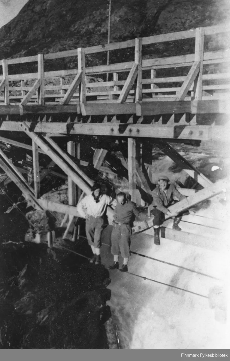En provisorisk bru over Adamsfossen, på riksveg 50, i 1946. Under selve brua ser vi tre personer, fra venstre: avd. ingeniør Johannes Holt, tekniker Grorud og oppsynsmann Johannes Foslund.