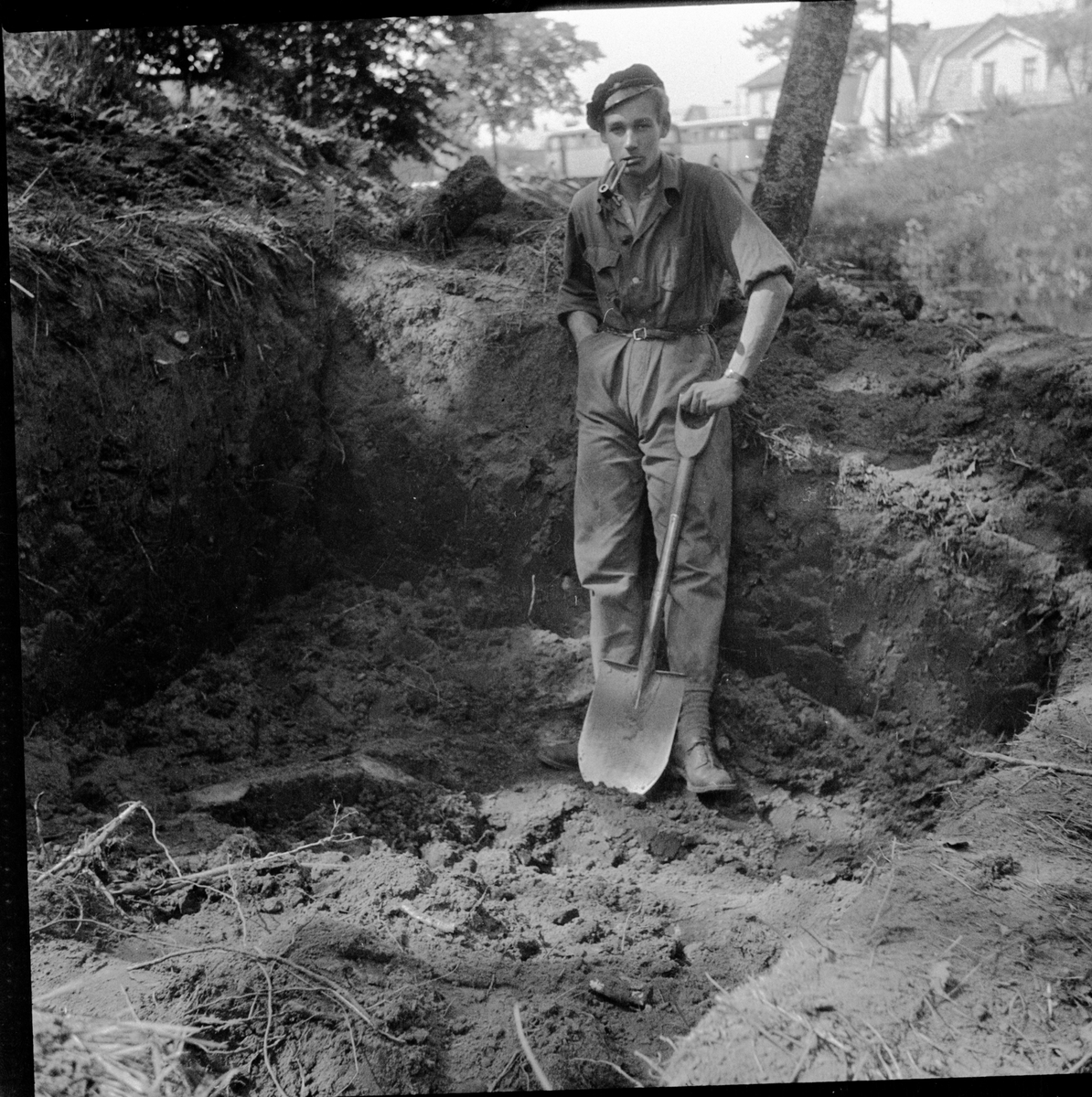 En ung man med spade fotograferad i schakt D2 vid nordöstra sluttningen till borgkullen vid Rumlaborg i Huskvarna. Schaktet togs upp i samband med arkeologiska undersökningar vid borgen sommaren 1935.