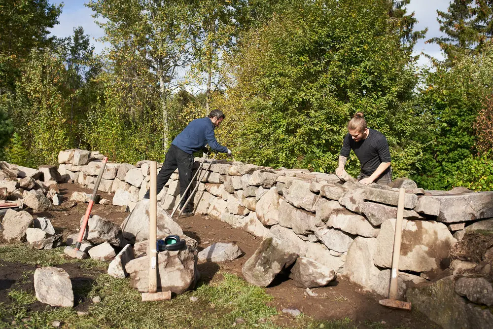 Foto av to mennesker som setter opp en steinmur.