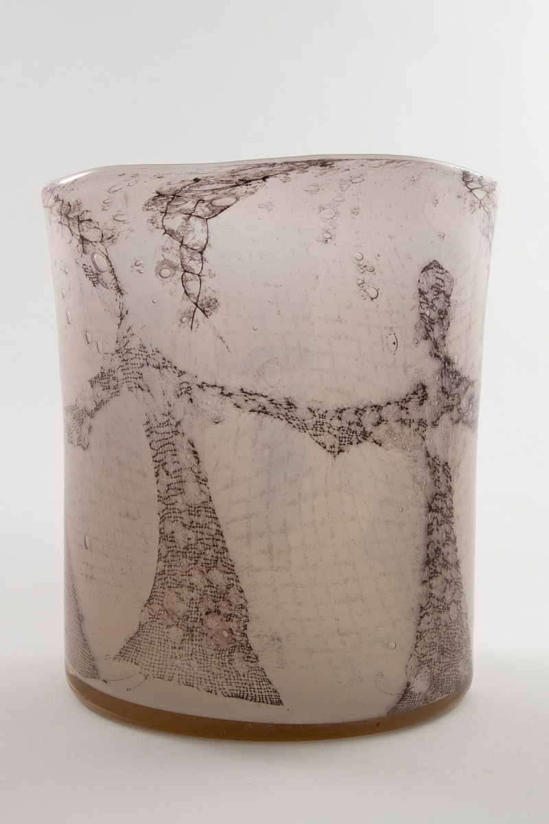 Høyreist ovalformet vase i grårosa glass med innlagt dekor av metallnett. Dekoren fremstiller stiliserte kvinnefigurer i en dansende bevegelse. Øvre del er svakt konisk og har en ujevn formet munningsrand.