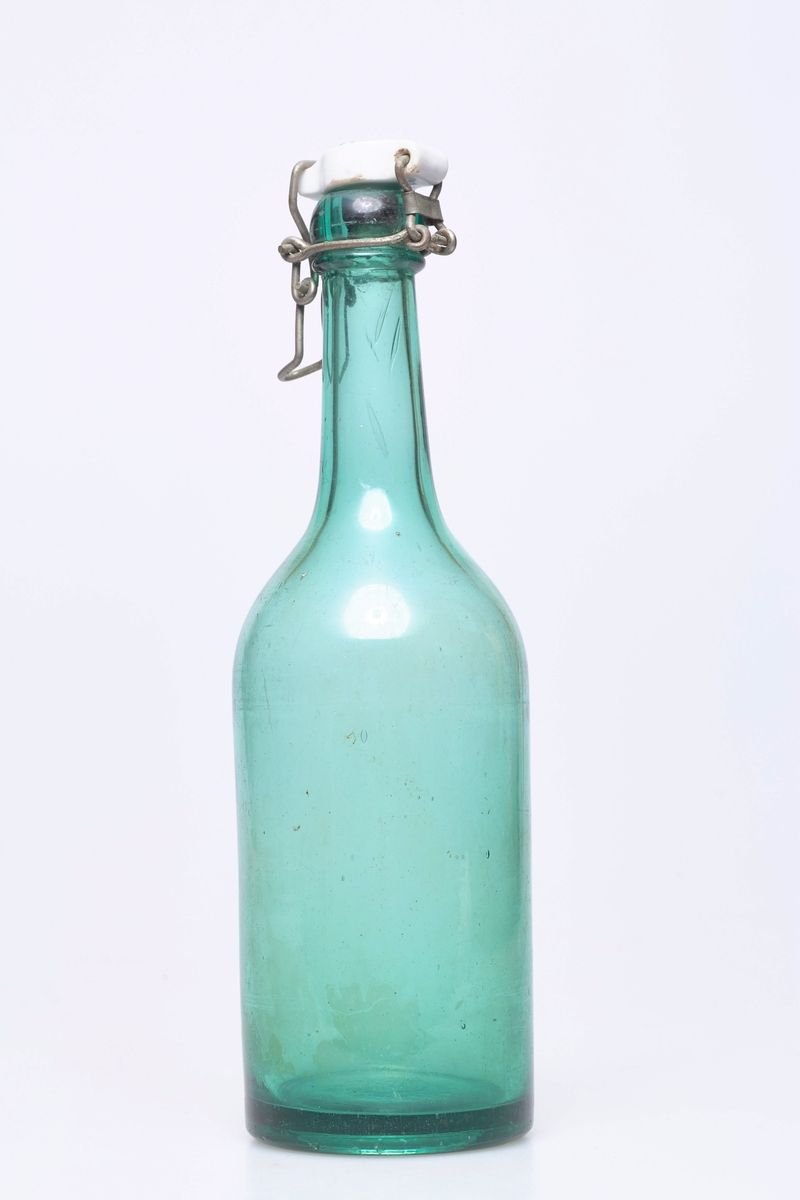 Glassflaske av grønt glass, med hvit plastkork med metallfeste.