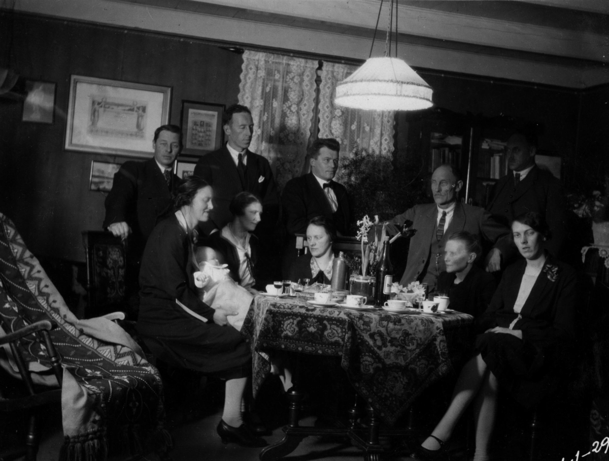 Helgesenfamilien inne i stua i hovedhuset på Fleskmo i 1929. Vi vet ikke anledningen, men familien og huset er pyntet til til fest. Det er svibler på bordet og sherry i glassene. Kan bildet være tatt i anledning Svanhild Nilssen Myhres barndåp?