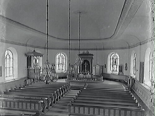 Interiörbild av Varbergs kyrka tagen efter renoveringen 1932, då bl a dekormålningarna målades över och bänkkvarterens utseende förändrades. Vy från läktaren över bänkarna mot koret.