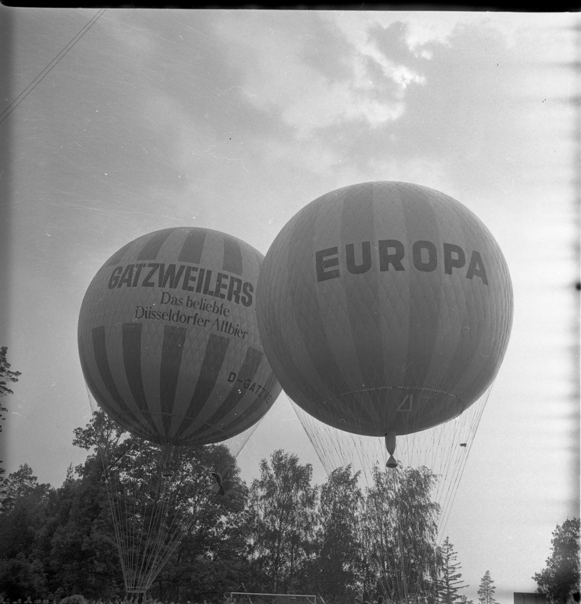 Två gasballonger på väg att lyfta, märkta "Gatzweilers Alt" respektive "Europa".