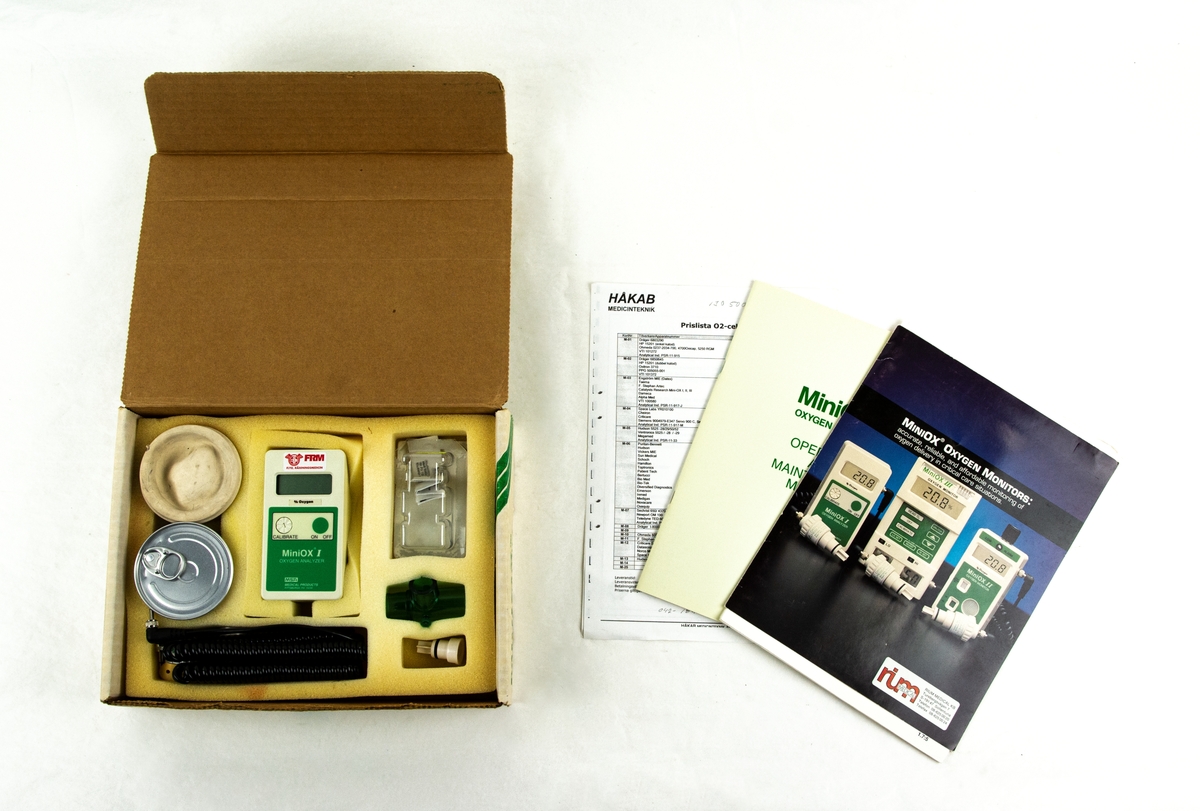 Syrehaltsmätare Miniox I, tillverkad av MSA medical products Pittsburgh USA. Förvaras i låda med tillhörande delar, manual och artiklar om flygande sjukvårdare.