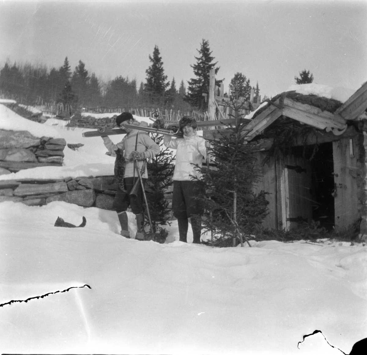 Kattunger og to personer med skiantrekk med nikkers som er klar for skitur med skiene på skuldera