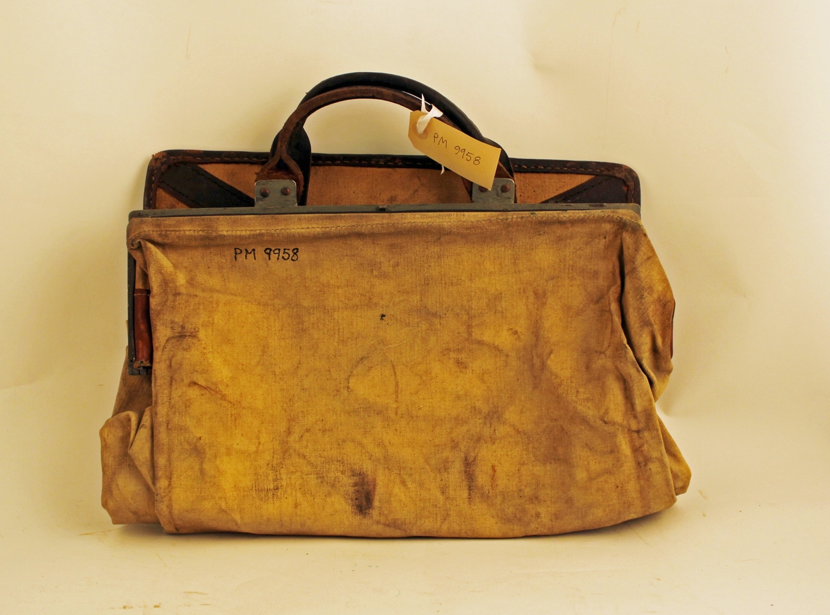 Tömningsväska av säckväv med järnarm (låsten) och läderskoning på den flata bottnen. Läderhandtag på ramen och bottnen gör att väskan kan bäras dubbelvikt.