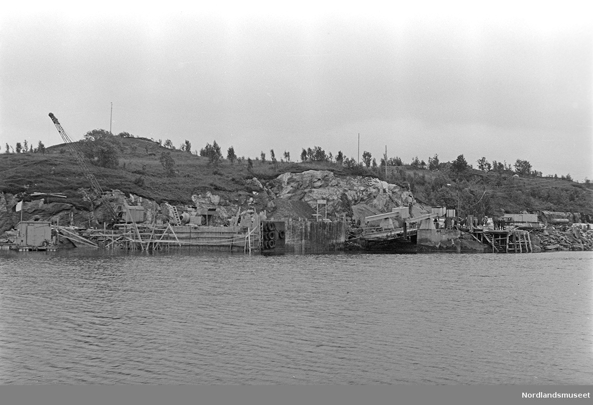 Fergeleie i Dønna? Bilde nummer 3 viser en kai med en større bygning og en båt litt til høyre ved kaien.