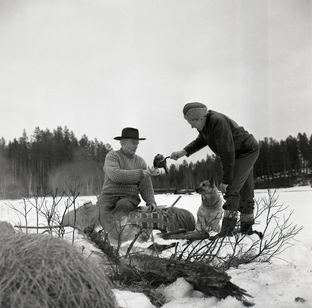 Hilding bjuder Albert på kaffe på Sillratjärns is och Alberts hund Nicko sitter bredvid, 4 april 1964.