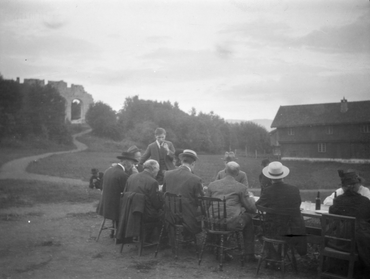 En gruppe mennesker ved et langbord nedenfor Domkirkeruinen på Hamar