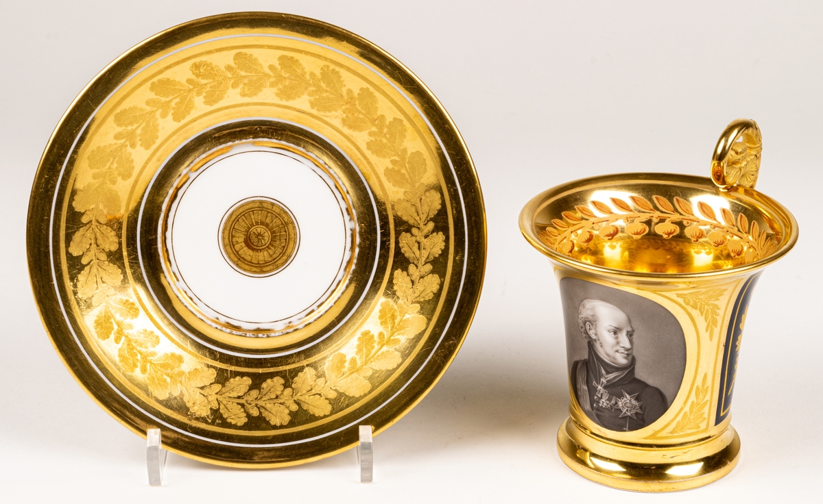 Karl XIII:S kopp.
Kopp med fat från Daite Freies i Paris, omkring 1800.
Koppens höjd 9.5 cm. Fatets diameter 16,5 cm.
Koppen bär på ena sidan Karl XIII:s bild och är på motstående sida dekorerad med ett par antika hjälmar.
Dekor i empirestil i guld och blått.
En grepe med örnhuvud och palmettdekor. Fatet är dekorerat med en eklövskrans.
