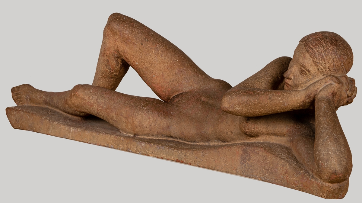 Skulptur, terrakotta, "Liggande kvinna" av Eric Grate. Naken kvinna ligger med ena knäet uppdraget, huvudet vridet halft åt sidan stött av båda händerna.