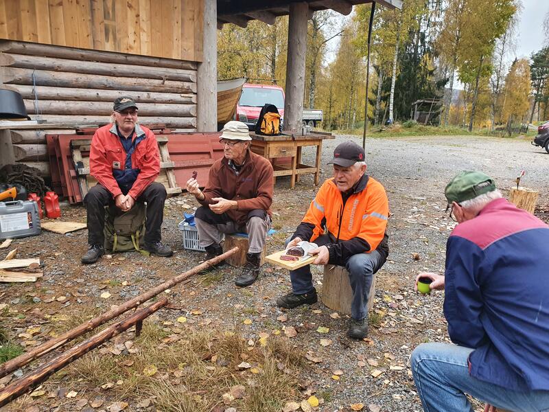 Dugnadsgjengen ved Eidskog museum tar en kaffepause i arbeidet med barking og brenning av staur til skigarden.