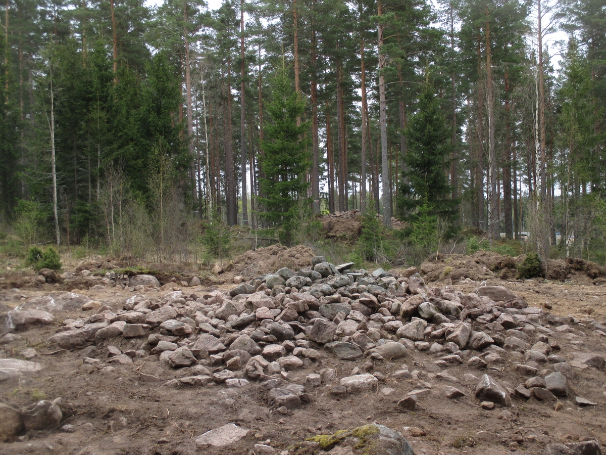 En förhistorisk grav, stensättning, efter framrensning. I bakgrunden syns ytterligare en framrensad stensättning. 

Bilden är tagen i samband med en arkeologisk förundersökning utanför Mullsjö, Jönköpings län.